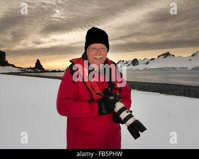 L'Antarctique, îles Shetland du Sud, demi-lune est, Baliza Hill, photographe mâle à l'aube avec vue sur l'île Livingston Banque D'Images