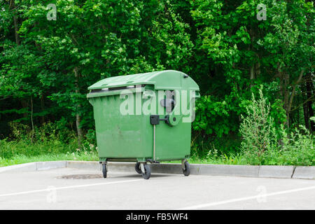Les conteneurs à déchets verts les coûts sur un parking automobile Banque D'Images