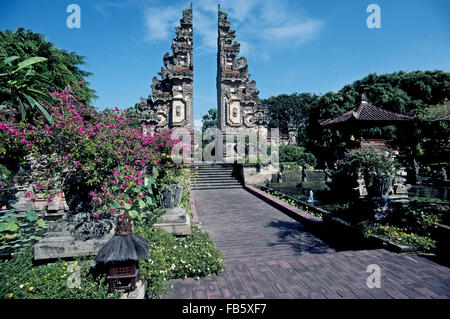 Un split balinais sculpté à la main gate appelé candi bentar mène dans un jardin tropical à l'hôtel 5 étoiles Nua Dusa Beach Hotel & Spa à Bali, en Indonésie, en Asie du sud-est. Je cherche comme une paire de serre-livres, cette immense entrée traditionnelle passerelle est sans logement avec deux côtés qui sont ornés d'images miroir. Banque D'Images