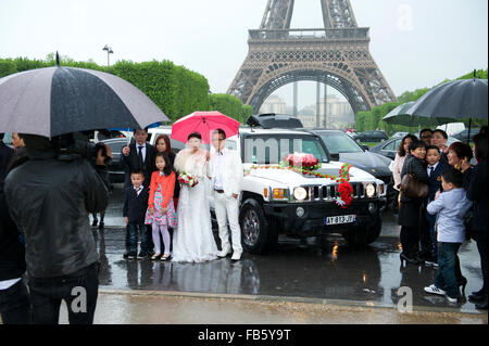 PARIS, FRANCE - Le 19 mai 2013 : Asian Bride and Groom holding parasols poser pour des photos en face de la Tour Eiffel. Banque D'Images