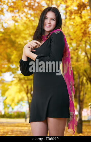 Belle fille en robe noire et foulard rouge en jaune du parc de la ville, saison d'automne Banque D'Images