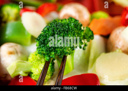 Les légumes fraîchement préparé avec des baguettes. Format de trame remplie avec l'accent sur le brocoli avant entre les baguettes. Banque D'Images