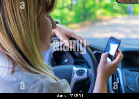 Femme regardant le téléphone au volant d'une voiture Banque D'Images