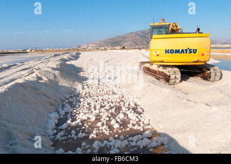 Italie, Sicile, Trapani. Une pelle sur chenilles Komatsu la récolte du sel de mer à partir d'un bassin d'évaporation. Banque D'Images