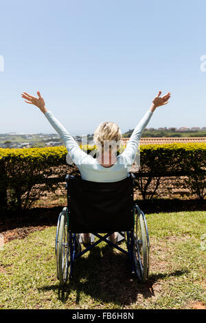 Vue arrière des personnes handicapées senior woman à bras ouverts dans le jardin d'accueil Banque D'Images