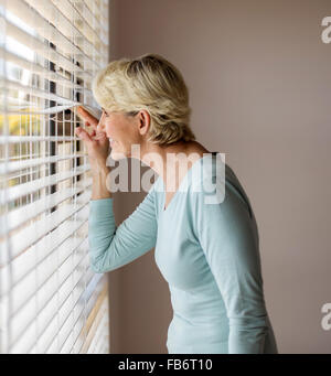 Happy senior man peeking through les blinds Banque D'Images