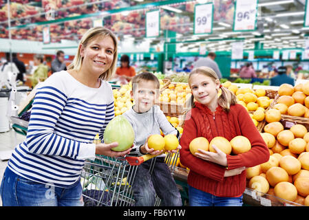 Mère et enfants avec fruits ananas en ministère dans le supermarché Banque D'Images