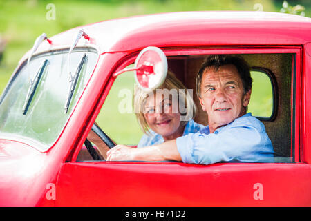 Senior couple in red car Banque D'Images