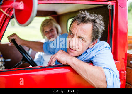 Senior couple in red car Banque D'Images