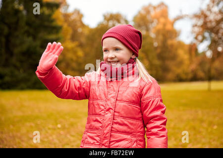 Happy little girl waving hand in autumn park Banque D'Images