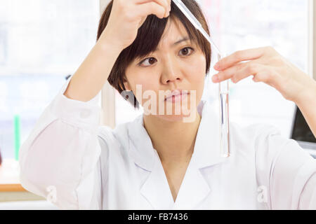 Femme scientifique chinois dropping liquid into test tube à la pipette Banque D'Images