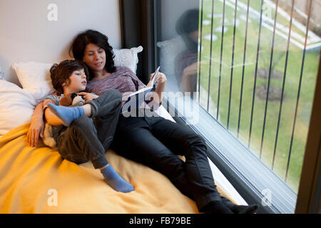 Mère et fils lying on bed and reading book Banque D'Images