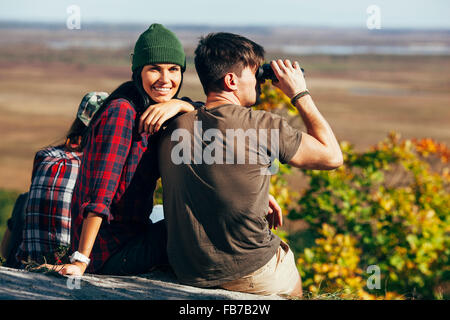 Jeune femme assise avec tes amis à l'aide de jumelles à forest Banque D'Images