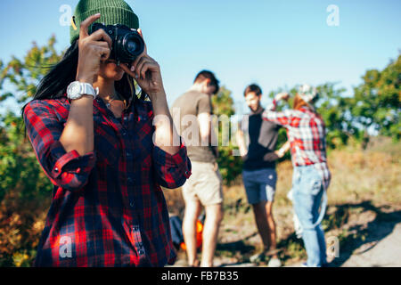 Young woman photographing tandis que friends standing in background Banque D'Images