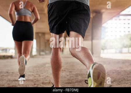 Portrait d'un coup de deux jeunes gens qui couraient sous le pont de la ville. L'accent sur les jambes de coureurs. Banque D'Images