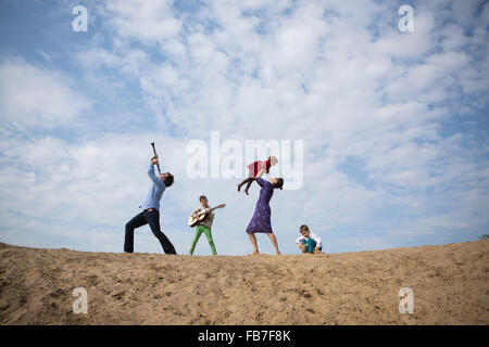 Low angle view of family enjoying on sand dune contre ciel nuageux Banque D'Images