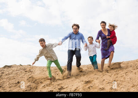 Family tout en appréciant sur dune de sable contre le ciel Banque D'Images