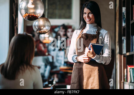 Waitress talking to female customer in coffee shop Banque D'Images