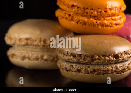 Pile de macarons colorés, couché sur fond noir Banque D'Images