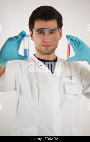 Jeune scientifique, portant robe blanche et bleu gants, tube de liquide coloré détient Banque D'Images
