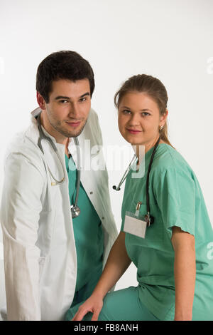 Couple de jeunes médecins, l'homme et de la femme, l'homme est vêtu de blanc et femme porte manteau vert (uniforme), les deux ont des stéthoscopes Banque D'Images