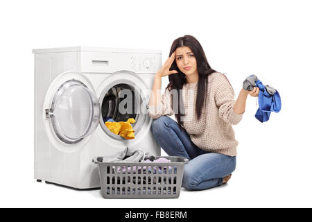 Portrait d'une femme triste vidange d'un lave-linge et regardant la caméra isolé sur fond blanc Banque D'Images