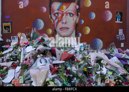 12 janvier 2016 Londres : les amateurs de musique anglaise emblématique artiste David Bowie qui est mort du cancer à l'âge de 69 ans le dimanche 10 janvier, se réunir pour rendre hommage à un sanctuaire de fortune de fleurs et des hommages à la garçon de Brixton, dans le sud de Londres. Les banlieusards arrêté par avant d'entrer dans la station de métro voisine pour prendre des photos et silencieusement se souvenir de leurs héros grands jours jouant les musiques de leur enfance. Richard Baker / Alamy Live News. Banque D'Images