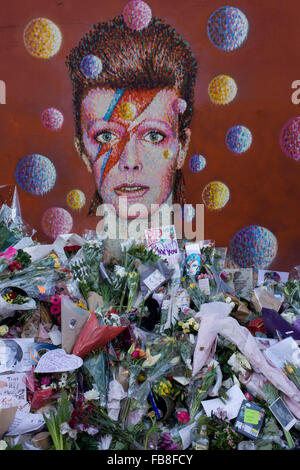 12 janvier 2016 Londres : les amateurs de musique anglaise emblématique artiste David Bowie qui est mort du cancer à l'âge de 69 ans le dimanche 10 janvier, se réunir pour rendre hommage à un sanctuaire de fortune de fleurs et des hommages à la garçon de Brixton, dans le sud de Londres. Les banlieusards arrêté par avant d'entrer dans la station de métro voisine pour prendre des photos et silencieusement se souvenir de leurs héros grands jours jouant les musiques de leur enfance. Richard Baker / Alamy Live News. Banque D'Images