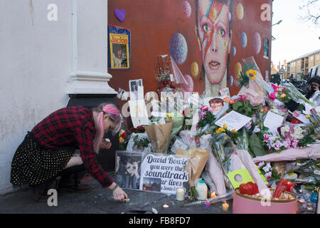 12 janvier 2016 Londres : les amateurs de musique anglaise emblématique artiste David Bowie qui est mort du cancer à l'âge de 69 ans le dimanche 10 janvier, se réunir pour rendre hommage à un sanctuaire de fortune de fleurs et des hommages à la garçon de Brixton, dans le sud de Londres. Les banlieusards arrêté par avant d'entrer dans la station de métro voisine pour prendre des photos et silencieusement se souvenir de leurs héros grands jours jouant les musiques de leur enfance. Richard Baker / Alamy Live News. Banque D'Images