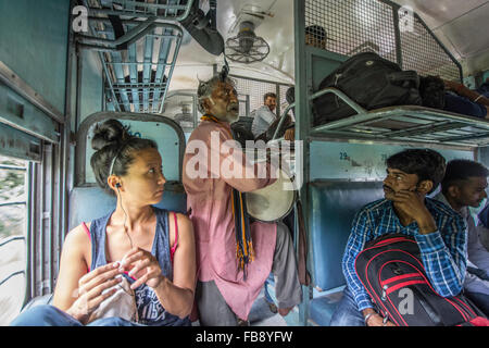 Musicien voyageur jouant pour les passagers d'un train indien. Banque D'Images