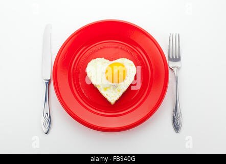 Valentine Petit-déjeuner avec des oeufs en forme de coeur sur un plat rouge Banque D'Images