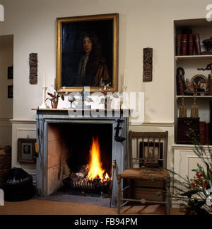 Portrait à l'huile au-dessus de cheminée avec le feu allumé dans la salle à manger pays Banque D'Images