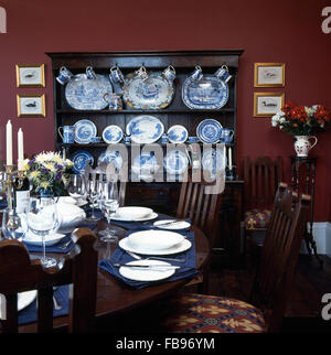 Set de table pour le dîner dans la salle à manger des années 90 rouge foncé avec une collection de bleu +blanc chine sur une commode en chêne Banque D'Images