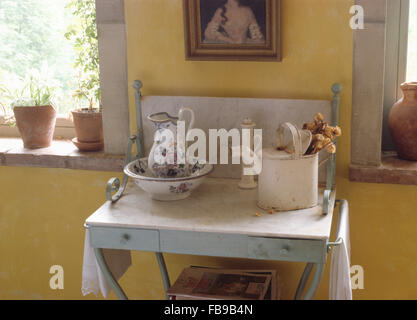 Pot à fleurs et bol sur lavabo en marbre avec un arrosoir peint vintage Banque D'Images