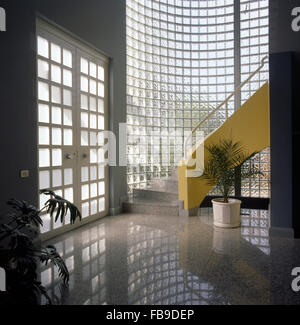 Escalier avec mur jaune en 1990 hall avec un mur en brique de verre courbé Banque D'Images