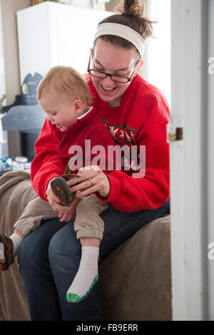 Denver, Colorado - une jeune femme l'habille 15-month-old fils. Banque D'Images