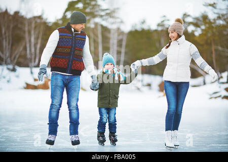 Jeune famille tenant la main et patinage sur glace Banque D'Images