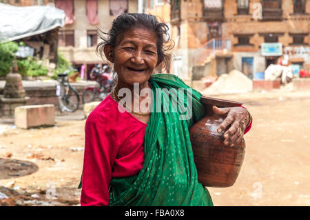 Vieille Femme dans une rue de village Khu portant une cruche d'eau Banque D'Images