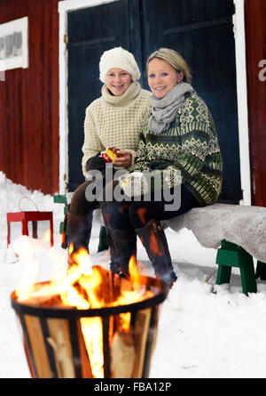 La Suède, Portrait de Mère assise avec teenage girl (14-15) sur le banc en hiver Banque D'Images