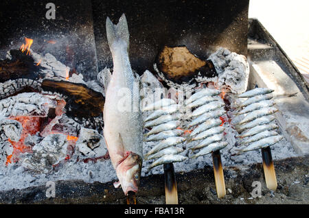 Lignes d'anchois et de sardines sur des brochettes en bois cuisson sur un barbecue sur la plage Playa de la Vénus à Marbella Banque D'Images