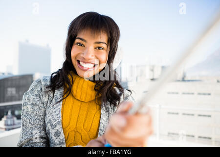 Femme souriante portant des vêtements d'hiver et prendre un selfies Banque D'Images