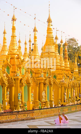 Les moines assis en face de prière posts en Paya Shwedagon, Yangon, Myanmar Banque D'Images
