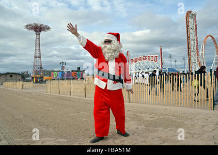 Un homme dans un costume père noël sur la plage de Coney Island, Brooklyn le jour du Nouvel An pour le Polar Bear Club de natation annuel. Banque D'Images