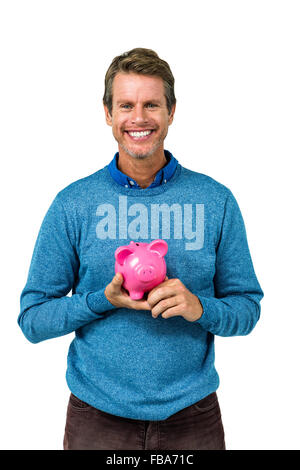 Portrait of smiling man holding piggy bank Banque D'Images