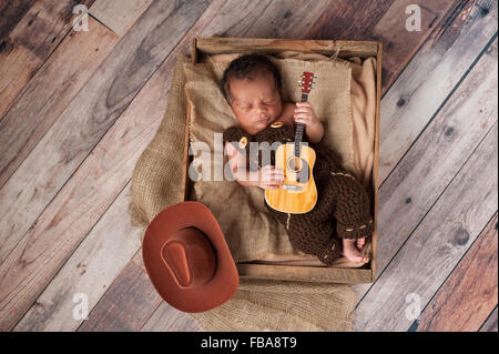 Bébé nouveau-né Cowboy jouant une petite guitare Banque D'Images