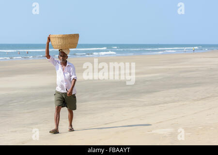 Un Indien vend des fruits et des boissons promenades le long d'une plage vide, plage de Mandrem, Nord de Goa, Inde Banque D'Images