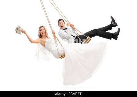 Portrait de jeunes époux et une épouse se balançant sur des balançoires en bois isolé sur fond blanc Banque D'Images