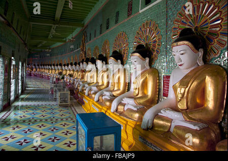 Longue rangée de Bouddhas en pierre peint contre un mur du temple vert dans l'ancienne capitale du Myanmar Sagaing Banque D'Images