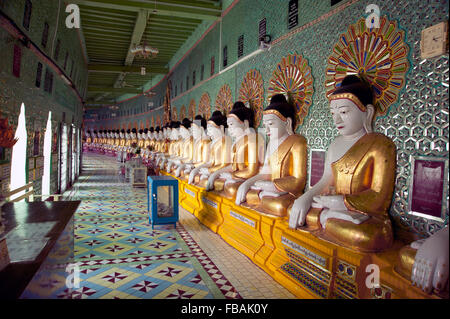 Longue rangée de Bouddhas en pierre peint contre un mur du temple vert dans l'ancienne capitale du Myanmar Sagaing Banque D'Images