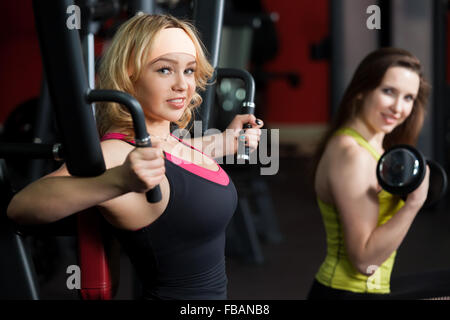 Deux copines sportive dans les vêtements de sport ne la formation de poids pour des bras et la poitrine avec des haltères et des appareils de formation sur ma papillon Banque D'Images